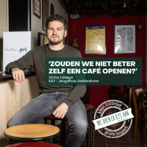 Een man met een baard zit op een barkruk in een gezellige kroeg. De tekst op de afbeelding luidt: "Zouden we niet beter zelf een café openen?" met dank aan Victor Farasyn van KAJ - Jeugdhuis Jonkershove. Er staat een postzegel met de tekst: "we doen er iets aan.