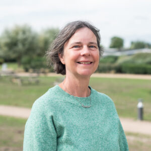 Ann Segers poseert met groene trui. In de achtergrond is wazig een park te zien.