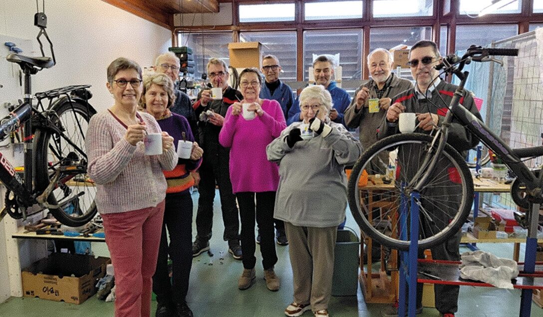 Tien vrijwilligers poseren met een tas soep in de hand in de fietsatelier van Fietsbieb Brugge.