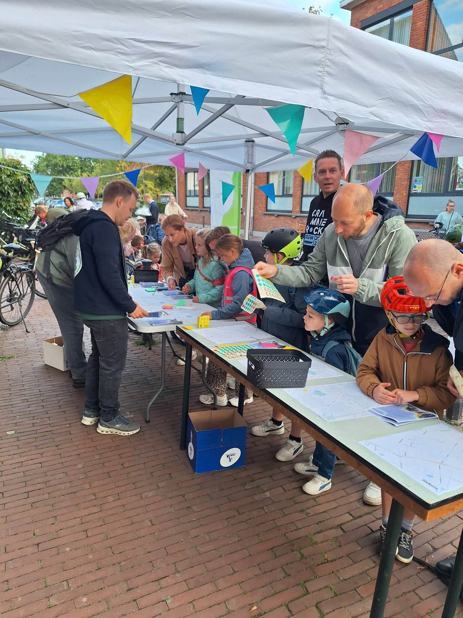 Ouders en kinderen bekijken de veiligste route naar school op stratenplannen die op tafels liggen.